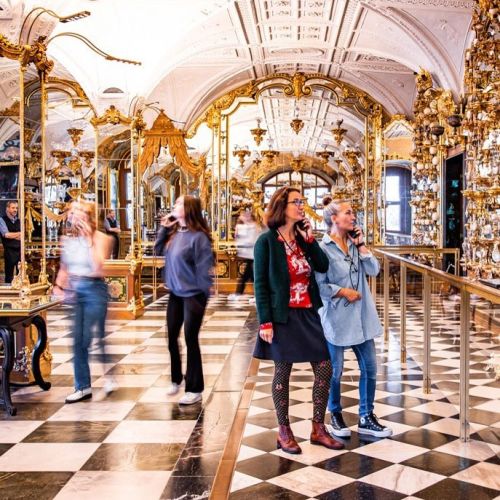 Besucherinnen sind im verspiegelten und prunkvollen Pretiosensaal mit ihren Audioguides unterwegs
© SKD, Foto: Carina Sonntag