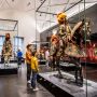Kinder bestaunen ein großes eisernes Pferd, auf dem ein Ritter in seiner verzierten Rüstung sitzt, im Riesensaal der Rüstkammer
© SKD, Foto: Carina Sonntag