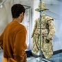Junge schaut auf ein grünes, detailreich verziertes Gewand mit einem dazu passenden Hut in der Ausstellung Macht und Mode 
© SKD, Foto: Carina Sonntag