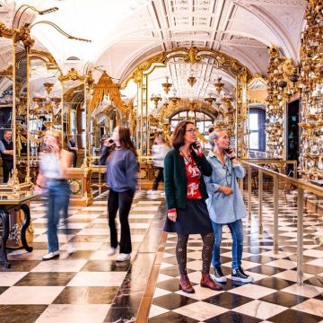 Besucherinnen sind im verspiegelten und prunkvollen Pretiosensaal mit ihren Audioguides unterwegs
© SKD, Foto: Carina Sonntag